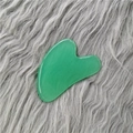 Green heart-shaped gua sha tool made of smooth jade resin on a plush background - Green Gua Sha Board