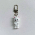 Détail macro du porte-clés chat blanc floqué avec texture douce et fermoir argenté - Boucle Porte-clés / Blanc