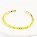 Detailopname van een gouden metalen open armband met heldergele emaille strepen - Geel