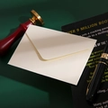 Beige mini kraft paper envelope displayed on a green background with vintage desk accessories - Off White
