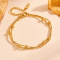 Cavigliera a doppio strato in acciaio inossidabile dorato con perline su texture beige - Bracciale in Oro a Doppio Strato con Catena a Serpente e Perline (L803)