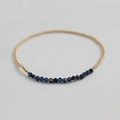 Macro detail of elastic beaded bracelet with faceted blue gemstones and gold beads - Kyanite