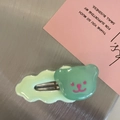 Close-up of a green bear-shaped hair clip with resin finish on a metallic background - Green