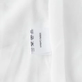Detail shot of the garment care label showing 100% Cotton material and washing symbols - 100% Cotton