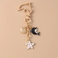 Detalle del llavero de delfín dorado con colgantes de concha, estrella de mar y perla - Delfín Negro