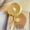 Détail d'une broche fleur en or mat avec centre en petites perles sur fond décoratif - Fleur Dorée Avec Perle Artificielle (Fleur 2.9*5.3cm)