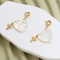 Macro detail of heart-shaped mother of pearl pendant with gold relief and cross charm - Heart Shape