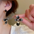 Détail de boucles d'oreilles vintage avec pétales noirs et perles portées par un modèle - Style Fleur Asymétrique Noir (33#)