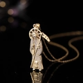Pendente Santa Muerte dorato con zirconi posto su una superficie nera riflettente - Parca 02 Zirconia Bianca