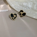 Macro detail of vintage heart earrings with black enamel and gold rose relief - Black Rose Relief