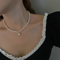 Elegant gold-tone pearl necklace with rice-shaped beads and round pendant on a model - French Vintage Pearl Necklace