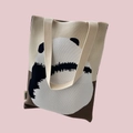 Close-up of knit tote bag detail with panda pattern and a small brand tag on the side - Cream Panda Back