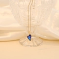 Detailed view of a purple glass heart pendant with a gold chain on white silk background - Dark Blue