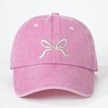 Close-up of pink washed baseball cap featuring white bow embroidery and textile texture - One Size / Pink