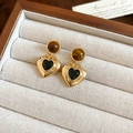 Macro-opname van vintage vergulde oorbellen met tijgeroog en hartvormige stenen in doos - Zwarte Hart Stijl / Goud
