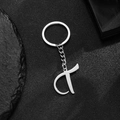 Polished stainless steel letter T keychain pendant on black stone textured background - Letter T