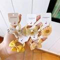 Detailed close-up of five yellow children's bow and flower hair ties on a display card - 5 Pairs Set / Yellow
