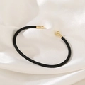 Detail shot of a black woven rope cuff bracelet with polished gold metal end caps - Black