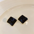 Square black enamel stud earrings with gold plating on a textured beige display tray - Black