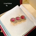 Detail view of a luxury gold brooch with three red gems in a jewelry box, 3.1cm by 0.9cm - D044 Red