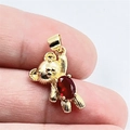 Gros plan d'un pendentif ours doré avec un zircon rouge facetté tenu sur le doigt - 6# Rouge + Collier