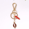 Golden metal keychain featuring a red sneaker charm and brown American football pendant - Gold Football Red Shoe Style