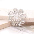 Macro detail of luxury flower brooch with center pearl and marquise crystal petals - White