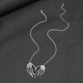 Gothic punk silver skeleton hands heart necklace on a dark textured background - Silver