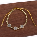 Dettaglio delle medaglie di San Benedetto e perline dorate su bracciale regolabile - Stile intrecciato a 3 medaglie