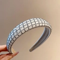 Dettaglio del cerchietto imbottito beige con strass grigi e motivo a griglia lucido - Bianco