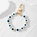 Macro shot of evil eye beads with golden lobster clasp and beads on a stone surface - White Flat Beads