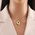 Dettaglio della collana con ciondolo lettera Q placcata oro 18K sul collo di un modello chic - Lettera Q