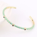 Détail d'un bracelet ouvert doré avec rayures émail vert menthe et accents noirs - Vert