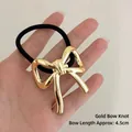 Golden bow elastic hair tie with geometric metallic finish and black stretchy band - Ribbon Bow Gold