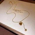 Close-up of golden snake chain necklace with brown heart resin pendant on textured cloth - Gold Brown Heart Ball Snake Chain