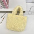Close-up of soft yellow plush tote bag with Sozakka label on a minimal white desk - Bright yellow