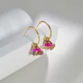 Macro shot of bohemian gold earrings with colorful natural stones on white stone - Colorful