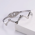 Dettaglio del bracciale rigido a onde argentato con strass su supporto in legno - Argento