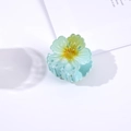 Detailed view of a 4.5cm translucent blue flower hair claw clip with glitter accents - Blue