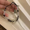 Detailed shot of handmade pearl and obsidian bracelet with a green butterfly charm - White/Butterfly Pendant