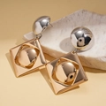 Detailopname van geometrische tweekleurige oorbellen op een witte stenen basis - Goud (Zilveren oorsteker)
