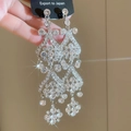 Close-up of sparkling diamond fringe earrings with layered wavy tassels and crystals - Silver Flower Style
