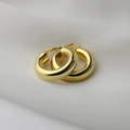 Close-up of chunky gold hoop earrings with mirror polish on white silk fabric - Polished Chunky Hoop / Gold