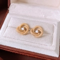 Makro-Detail von Vintage Gold Ohrringen mit Perle und Knotendesign in einer Schmuckbox - Gold