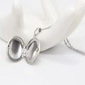 Polished silver oval locket necklace shown open on a white hand display stand - Necklace - Silver Oval / Glossy