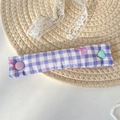 Macro detail of purple checkered fabric cable organizer with pink bow and heart buttons - Purple Gingham Bow