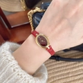 Primer plano del elegante reloj ovalado dorado con esfera roja y correa de cuero roja - TT-Esfera Ovalada