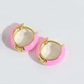 Detailaufnahme der rosa emaillierten Creolen mit poliertem goldenem Metall-Finish - Rosa