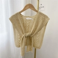 Beige knitted shawl vest with cutout pattern and front tie design on a wooden hanger - Off White