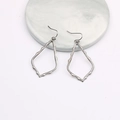 Macro detail of irregular hollow leaf earrings on a marble base with metallic finish - Gun Black